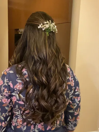 A full back view of this romantic hairstyle. The long, flowing curls are gathered neatly and accented with a simple floral touch.