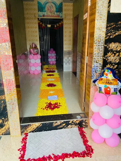 A welcoming home entrance with a flower petal walkway and balloon pillars for a newborn's arrival.