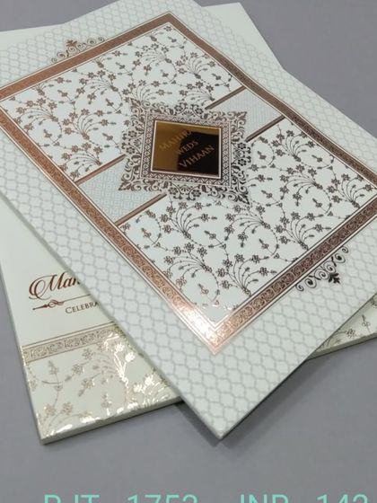 This invitation features a classic white and gold design with intricate patterns. The look is timeless and luxurious, perfect for a grand wedding.