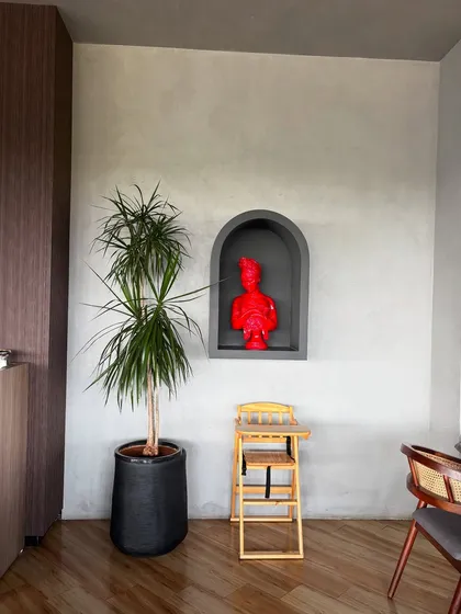 A Dracaena plant stands next to a modern art piece, showing how natural forms can complement artistic ones. The simplicity of the plant balances the boldness of the red sculpture.