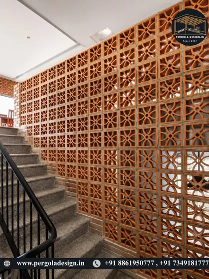 A terracotta jali wall along a staircase, providing a safety barrier that is also a stunning design feature. The pattern adds visual interest and texture to what is often a purely functional area.