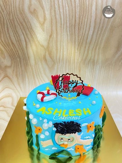 Making a splash with this swimmer-themed cake. It's decorated with a hand-painted swimmer, bubbles, and a lifebuoy for a fun pool party vibe.