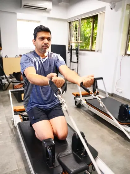 Real men do Pilates. This client performs a kneeling row on the reformer, an exercise that builds a strong back and core, which is crucial for athletic performance and preventing back pain.