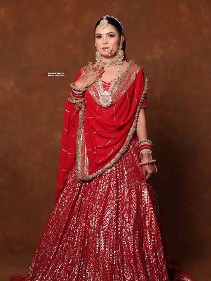 A full view of the bride's magnificent red lehenga. The simple, elegant updo ensures that the focus remains on the incredibly detailed embroidery and heavy jewelry.