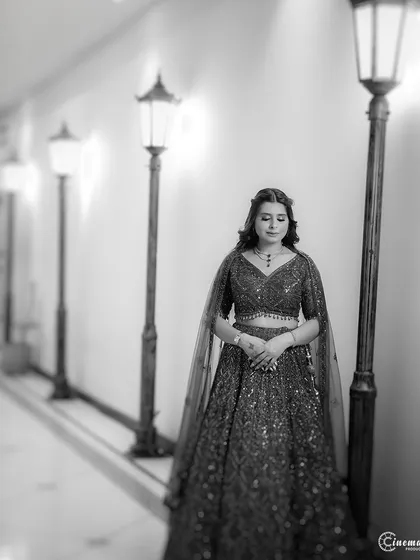 A solitary bridal portrait in black and white. The composition uses leading lines from the row of lamps to draw the eye and create a moody, artistic shot.