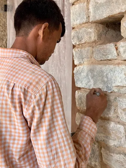 A craftsman delicately works on the stone wall, a task requiring patience and a steady hand. This close-up highlights the human touch that defines our approach to reviving traditional craftsmanship.