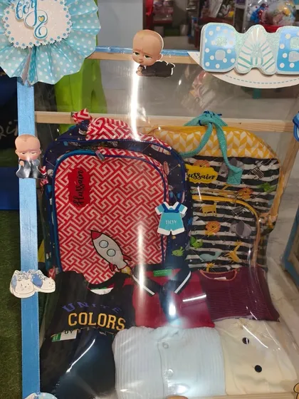 A hamper featuring a personalized backpack and a collection of t-shirts for the baby boy.