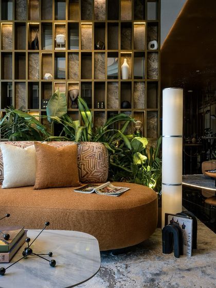 Detail of the lounge seating, highlighting the custom-patterned upholstery and the sculptural floor lamp. The backlit grid wall serves as both a bookshelf and a mood board, adding layers of texture and personality.