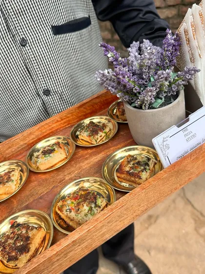 A tray of our delicious garlic cheese bread, served in individual golden dishes. This image shows our professional server presenting the appetizers, highlighting our courteous and well-groomed staff.