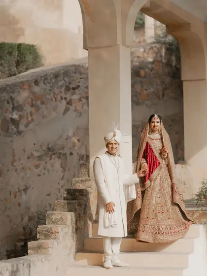 An elegant portrait of the couple on the steps of a palace, looking regal in their wedding attire.
