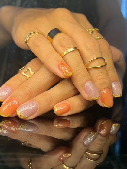 A full view of the beautiful orange and glittery nude nail set.