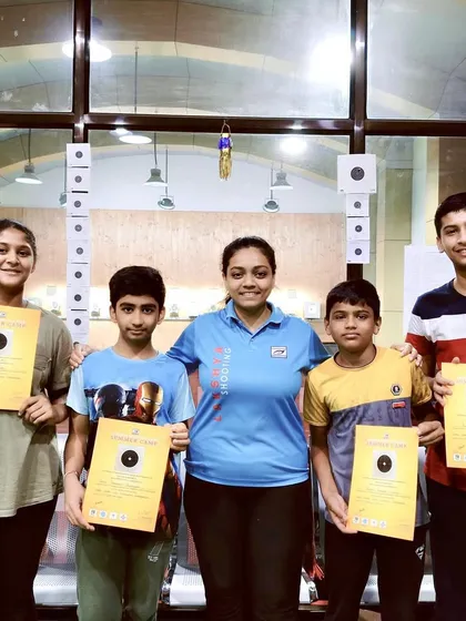 A coach poses with her group of summer campers, who are proudly holding their certificates and targets. This highlights the personal connection my coaches build with their students.