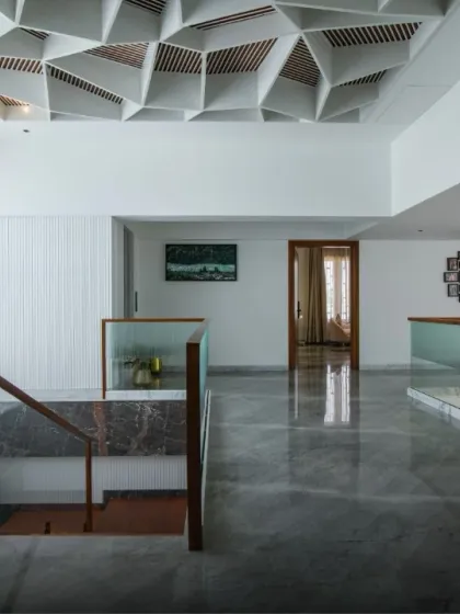 A stunning geometric coffered ceiling serves as a sculptural canopy over this hallway. The intricate design adds depth and character, turning the ceiling into a major focal point of the home.