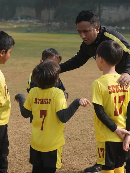 A coach giving instructions to his team. We create an environment where young talents can thrive, both on and off the field.