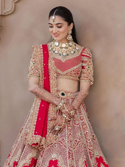 This image shows the intricate details of the regal red lehenga. The minimal makeup ensures the outfit remains the star of the show.