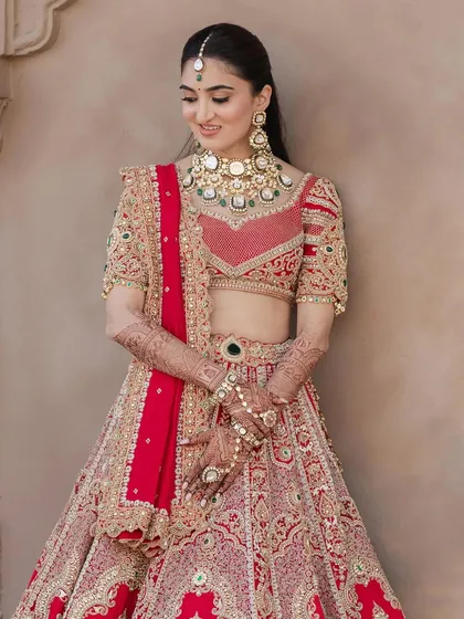 This image shows the intricate details of the regal red lehenga. The minimal makeup ensures the outfit remains the star of the show.