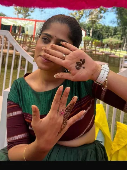 A happy client showing off her simple yet beautiful henna. We did a small lotus buti on the back of one hand and a single finger design on the other.
