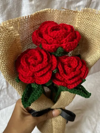 A handheld view of our classic three-rose bouquet. The vibrant red crochet roses look so striking against the natural burlap wrapping.
