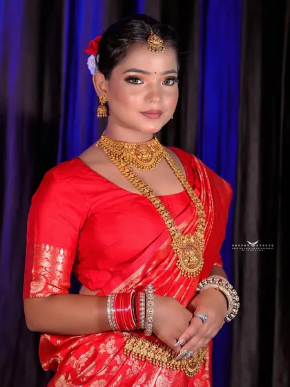 A classic portrait of the model in her red saree, showcasing the beautiful gold jewelry.