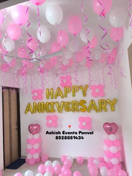 A beautiful pink and white anniversary decoration. The room is filled with ceiling balloons, balloon pillars, and 'Happy Anniversary' foil letters.