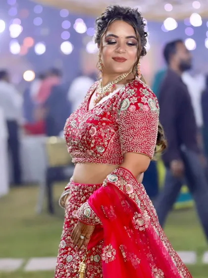 Ready for her brother's wedding in a stunning red lehenga. The makeup is glamorous with a braided updo.