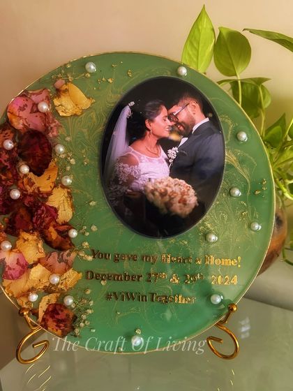 A full view of the sage green varmala preservation plate, displayed on a stand. The color provides a beautiful contrast to the red and yellow preserved petals.