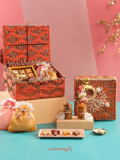 Our orange woven jute hamper is a burst of warmth and rustic charm. Filled with sweets and decorative potlis, it’s a gift that tells a story of love and care.