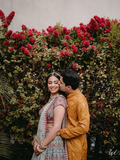 A romantic kiss against a backdrop of red bougainvillea. The soft makeup look is perfect for these intimate, candid shots.
