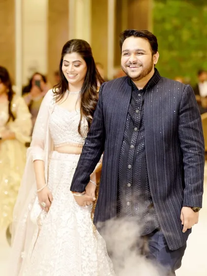 The couple's grand entrance at their engagement party, walking hand-in-hand through theatrical smoke.