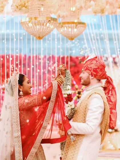 A sweet moment from an Indo-Western wedding ceremony, capturing the blend of cultures in the couple's attire and the rituals.