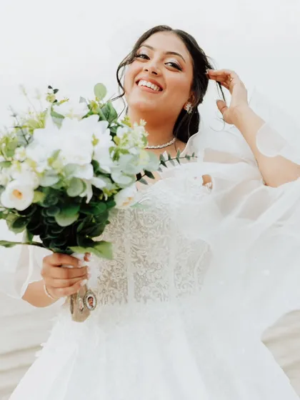 The pure joy of a bride on her wedding day. This candid shot on the beach captures her happiness, with wind-swept hair and natural makeup that looks effortless and beautiful.