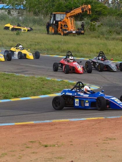 A view of the race track with multiple Formula LGB cars navigating a corner, showcasing the excitement of open-wheel racing.