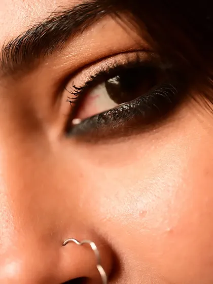 An extreme close-up of an eye and a heart-shaped nose ring. This artistic shot focuses on small, intimate details, adding a touch of modern romance to a traditional aesthetic.
