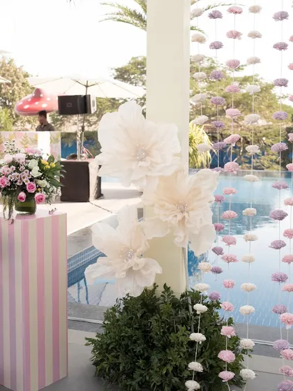 Giant paper flowers and striped decor elements add a touch of whimsy to the poolside Mehendi.