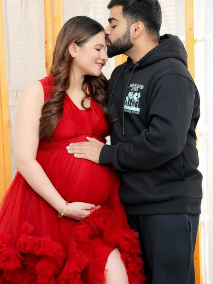 A gentle forehead kiss is a simple but powerful expression of love and protection. This close-up shot focuses on the tender bond between the expecting parents.