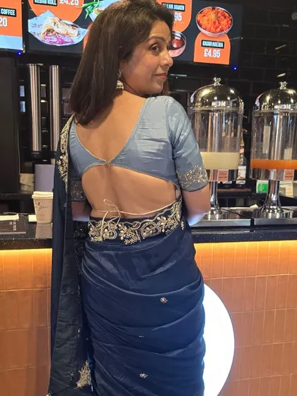 A back view of the deep teal blue saree, highlighting the stylish, deep-back blouse design.