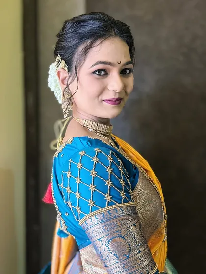 The beautiful detailing on the blouse sleeve complements the traditional hairstyle, which is adorned with a hair accessory.