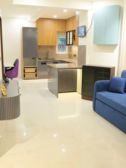 This is a great example of an open-plan living space I designed. The layout connects the living room, dining area, and kitchen, creating a bright and airy feel. The vibrant blue sofa adds a pop of color against the clean, modern finishes.