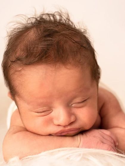 The classic 'head on hands' pose is perfect for showing off your baby's delicate features and full head of hair.