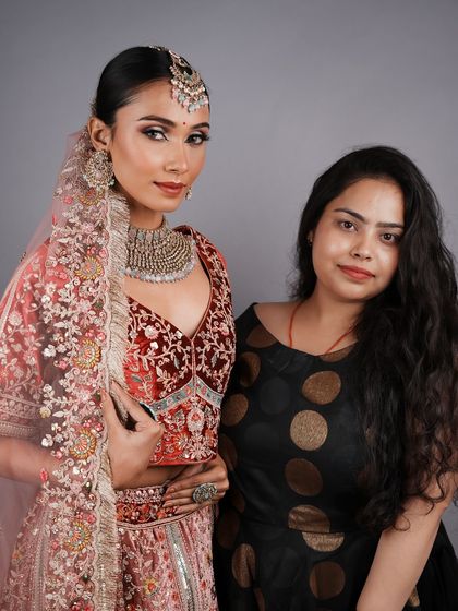 A student with her model, showcasing a beautiful red and pink bridal look. My course culminates in a professional photoshoot to kickstart their careers.