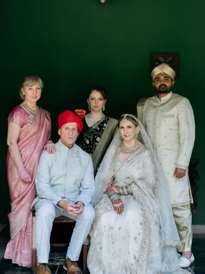 A beautiful family portrait from a wedding, where the bride's dark henna stain is visible, adding a traditional touch to her modern bridal look.