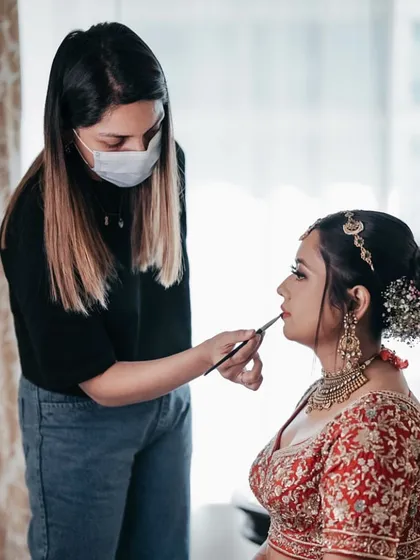 A closer look at the process. Here, I am applying lipstick while the hairstylist works on her intricate floral bun, a perfect example of teamwork.