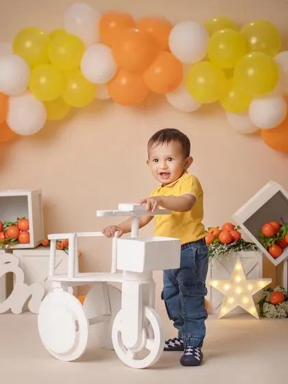 "Hey Dad, look at me!" A proud little boy stands by his first bicycle during his orange-themed first birthday shoot.