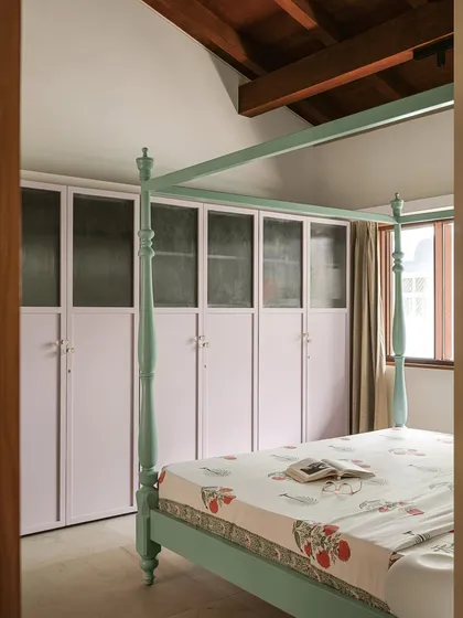 In this bedroom, a mint-green four-poster bed is paired with lilac-painted wardrobes. The contrast of colours, along with the traditional form of the bed and the simple lines of the cabinetry, creates a space that is both whimsical and contemporary.
