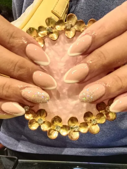 A chic and understated design with a neutral beige base, a fine white reverse French line, and glitter accent nails.