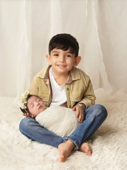 A proud big brother sits with his new baby sister on his lap. I work to make older siblings feel special and important during newborn sessions.