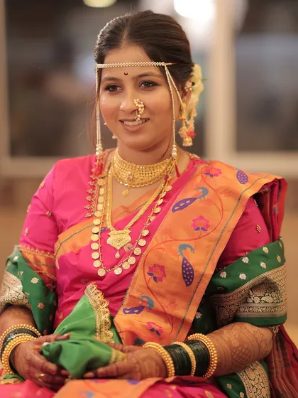 A happy bride, fully adorned with traditional Maharashtrian jewelry and headwear.