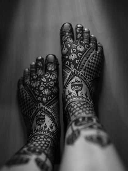 A black and white artistic shot of a bridal feet design, focusing on the beautiful patterns and the contrast of the henna.