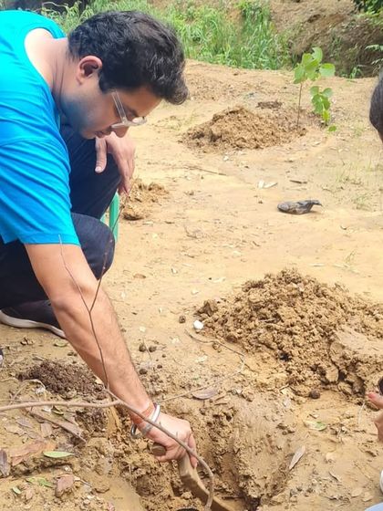 A volunteer from our long-standing partner, NTT DATA, carefully places a native Aravali sapling into the soil along the banks of the Sector 56 creek. This helps strengthen the creek and prevent erosion.