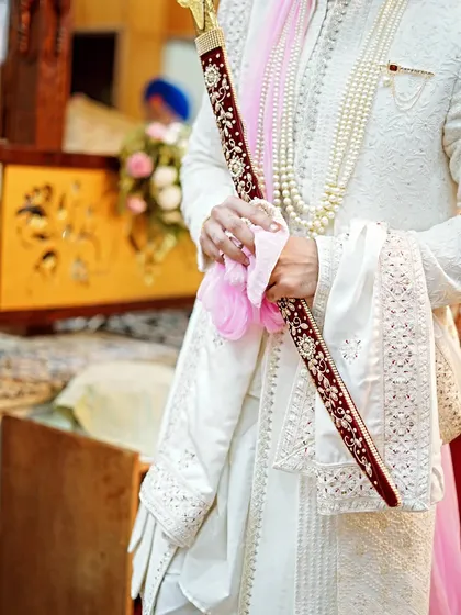 A detail shot of the Sikh groom holding the kirpan during the Anand Karaj ceremony. Capturing these traditional elements is key to telling the full story.